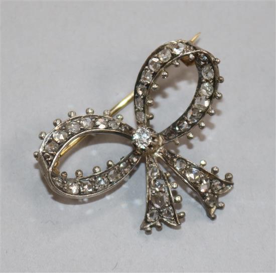 An Edwardian yellow metal and diamond set ribbon bow brooch, 33mm.